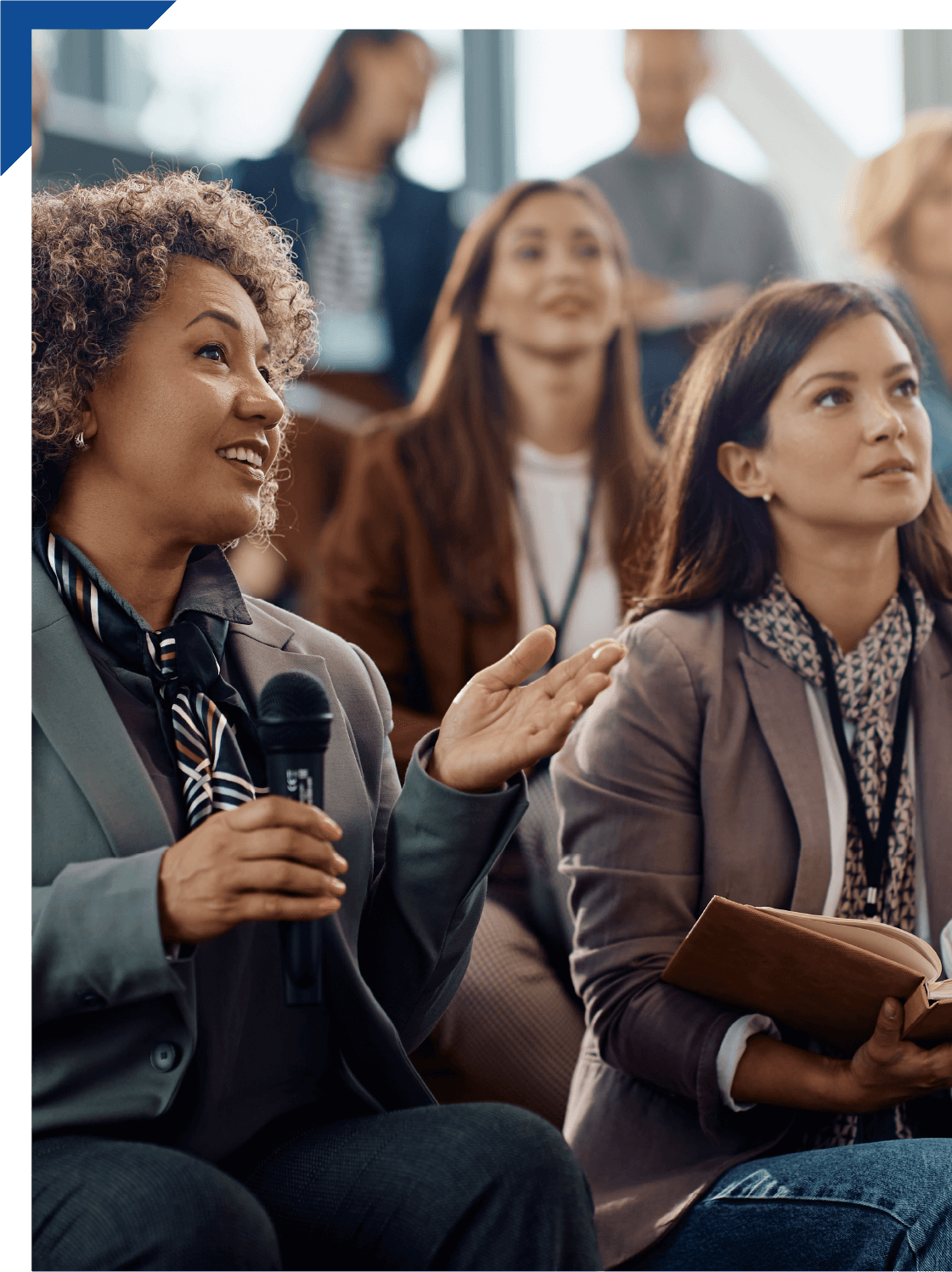 Happy businesswoman talking on microphone while attending education event in conference hall.